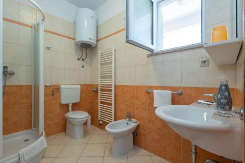 a bathroom with a toilet and a sink and a tub and a shower at Apartments ANIMA ex Marin in Podstrana