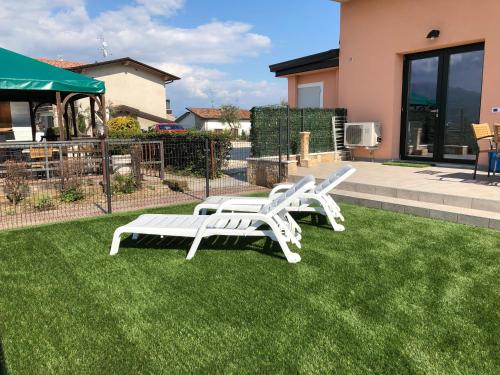two white lounge chairs on a lawn in front of a house at Residence Bellavista in Manerba del Garda