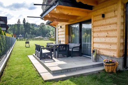 a wooden cabin with a table and chairs on a patio at Magiczny Domek in Białka Tatrzanska