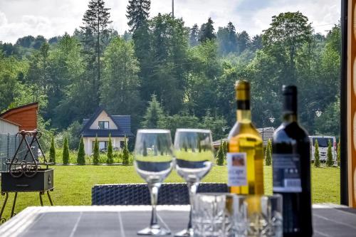 a table with two wine glasses and a bottle of wine at Magiczny Domek in Białka Tatrzanska