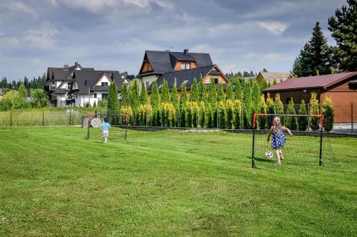 two children playing a game of soccer in a field at Magiczny Domek in Białka Tatrzanska
