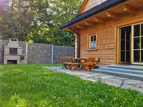 a patio with two wooden benches next to a house at Złoty Dom Brenna in Brenna