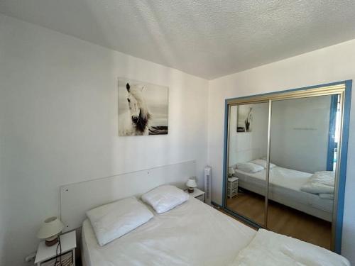 une chambre blanche avec un lit et un miroir dans l'établissement L'Albatros, à Gruissan