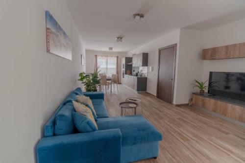 a living room with a blue couch and a kitchen at Brand new Apartament in Marsalforn in Żebbuġ