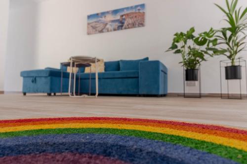 a living room with a blue couch and a rainbow rug at Brand new Apartament in Marsalforn in Żebbuġ