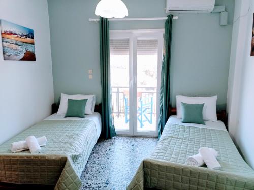 two beds sitting in a room with a window at Sunny Day Studios in Skala Marion