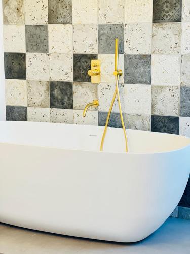 a white bath tub in a bathroom with a tiled wall at Gerani Deluxe Houses in Astypalaia Town
