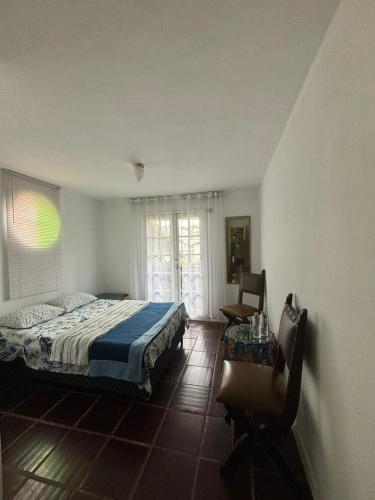 a bedroom with a bed and a chair and a window at Flat Muqui 91 in Teresópolis