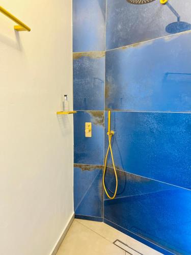 a blue tiled bathroom with a shower with a yellow hose at Gerani Deluxe Houses in Astypalaia Town