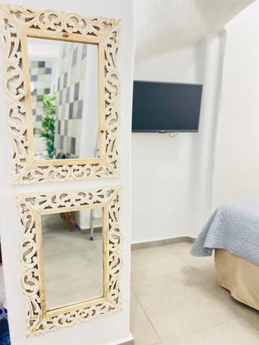 a mirror with a carved wooden frame in a bedroom at Gerani Deluxe Houses in Astypalaia Town