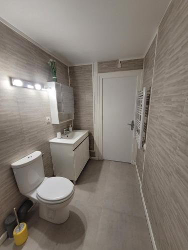 une salle de bain avec des toilettes blanches et un lavabo dans l'établissement Appartement en plein centre, à La Turballe