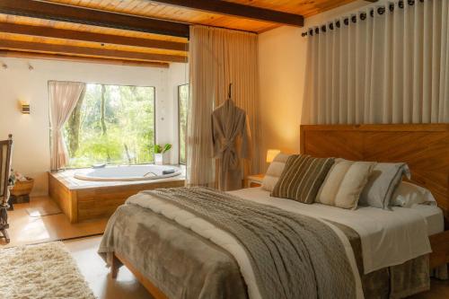 a bedroom with a large bed and a bath tub at Casa da Mata in São Bento do Sul