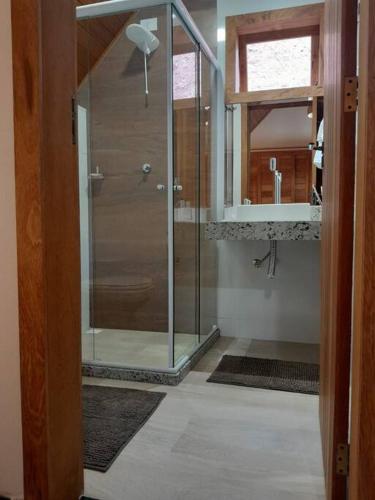 a bathroom with a glass shower and a sink at Chalé Sognare Uno in Santa Teresa