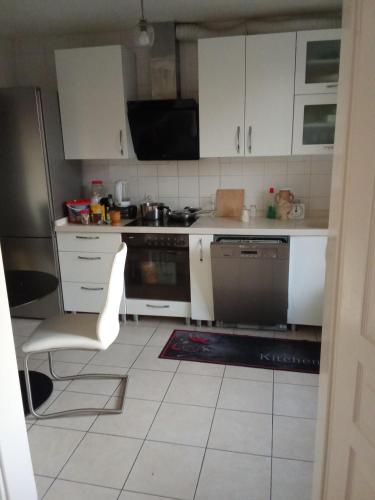 Il comprend une cuisine avec des placards blancs et du carrelage blanc. dans l'établissement Zimmer in eine whg in 63 rue des abeilles, à Mulhouse