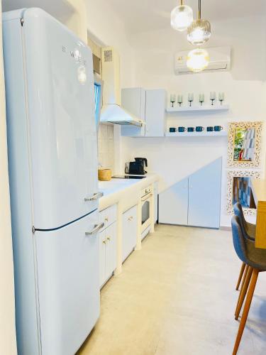 a white refrigerator in a kitchen with white cabinets at Gerani Deluxe Houses in Astypalaia Town