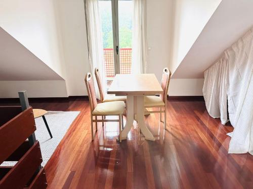 a dining room with a table and chairs and a window at Elegante Adosado en Ampuero in Rasines