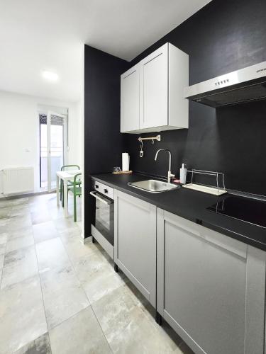 a kitchen with black walls and white cabinets and a sink at OOTA Soko with Parking Garage in Kragujevac