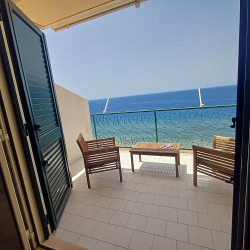 two benches and a table on a balcony with the ocean at Ionio in Reggio Calabria