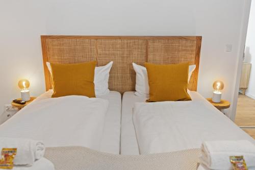 a bedroom with two beds with yellow pillows at ma suite - High-quality new apartment Augsburg in Augsburg