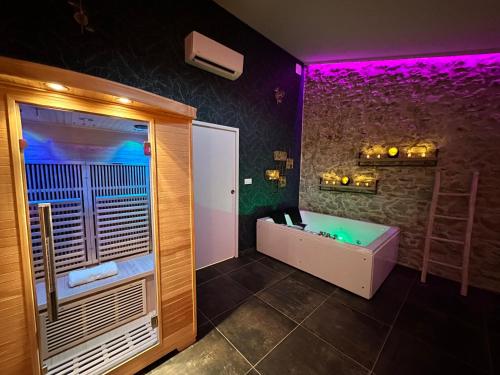 a bathroom with a tub and a shower with purple lights at Loft Romantique la Clef des Sens - Sauna et Balnéo privatifs in Tourves