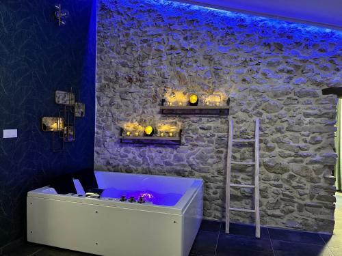a bath tub in a room with a stone wall at Loft Romantique la Clef des Sens - Sauna et Balnéo privatifs in Tourves