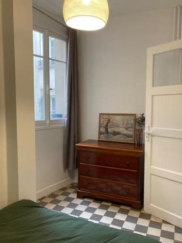 une chambre avec un lit, une commode et une fenêtre dans l'établissement Louvre apartment, à Paris