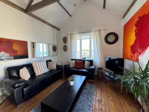 a living room with a black couch and a tv at Longsands Beach Apartment 3 Tynemouth Free Onsite Parking in Tynemouth