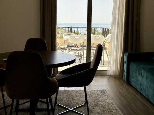 a room with a table and chairs and a balcony at Akhdar Apartments in Utjeha