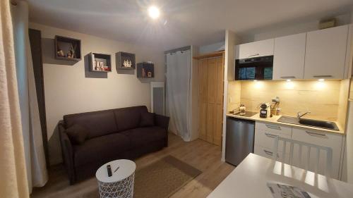 un petit salon avec un canapé et une cuisine dans l'établissement Studio au pied des remontées/wifi/smart TV/parking, aux Contamines-Montjoie