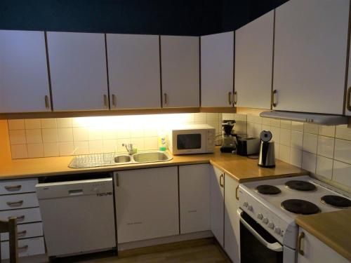 a kitchen with white cabinets and a stove top oven at Fjordshelter vintage townhouse in Tysso
