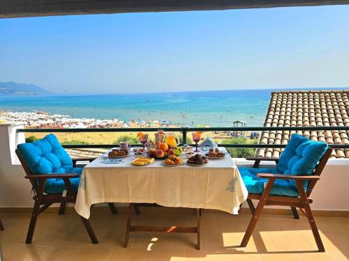 a table with food and a view of the ocean at Breeze Beach Apartment Glyfada in Corfu