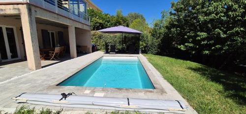 a swimming pool with an umbrella next to a house at "L'appart Idéal" in Deyme