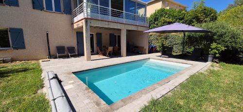 a swimming pool with an umbrella next to a house at "L'appart Idéal" in Deyme