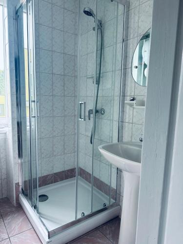 a shower with a glass door next to a sink at NB Apartamentai in Palanga