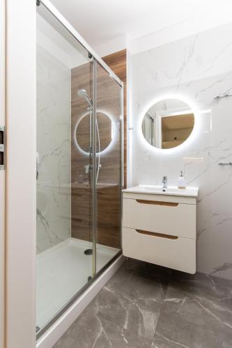 a bathroom with a shower and a sink and a mirror at Morski Apartament 50 m od plaży ApartPark in Świnoujście