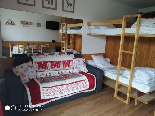 Cette chambre comprend deux lits superposés et un lit avec une couverture. dans l'établissement STUDIO 6 PERS LE BOIS D'AUROUZE 2eme étage NORD, à Superdevoluy