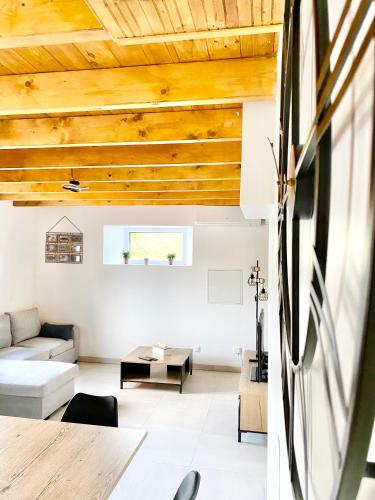 Elle comprend un salon doté de plafonds en bois et d'un canapé. dans l'établissement LA Conciergerie 05 - Gîte de la coopérative - Superbe Maison à L Epine - Wifi - 4 à 6 personne, à LʼÉpine
