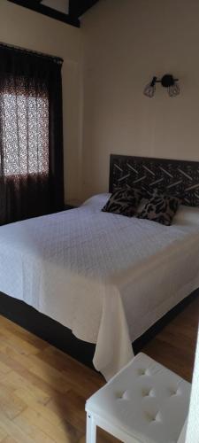 a bedroom with a white bed and a window at Casa rural La Abuela in El Ronquillo