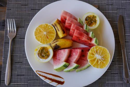 a white plate with fruits and vegetables on a table at Mambo Cabana in Pwani Mchangani