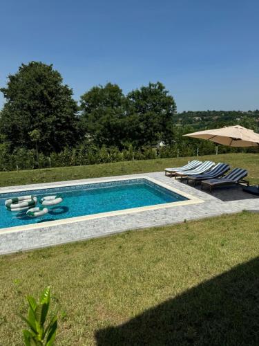 a swimming pool with lounge chairs and an umbrella at K42 pool house in Vlasi