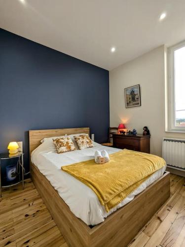 une chambre avec un grand lit avec un mur bleu dans l'établissement Parenthèse en centre ville, à Roanne