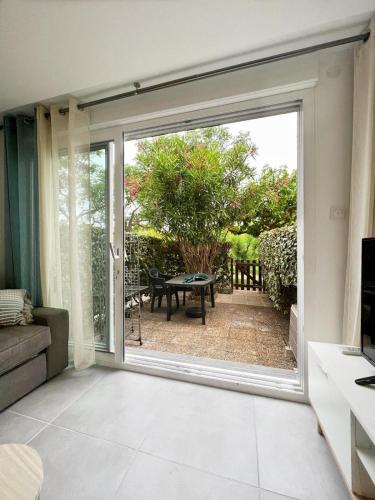 d'un salon avec une porte coulissante en verre s'ouvrant sur une terrasse. dans l'établissement Appartement 4 personnes, Piscine, Parking à Palavas les flots, à Palavas-les-Flots