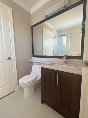 a bathroom with a toilet and a sink and a mirror at Near Skytrain and QUIET Private Bedroom Ensuite BathRM, Free Wifi & Coffee, Cozy in Burnaby