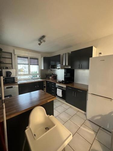 Il comprend une cuisine équipée d'un réfrigérateur blanc et d'un comptoir en bois. dans l'établissement Grande Maison proche Paris 10 12 personnes, à Bagnolet