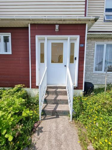 a red house with a white door and stairs at Appartement indépendant rez-de-chaussée in Saint-Pierre