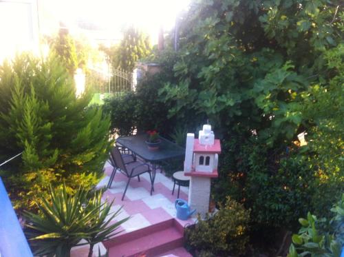 a small garden with a table and a bird house at Roses Apartments in Néa Michanióna