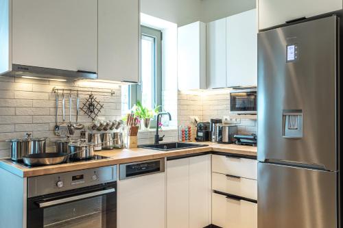 a kitchen with white cabinets and a stainless steel refrigerator at Lakkos Villas in Kardamili