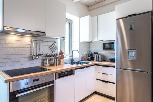 a kitchen with white cabinets and a stainless steel refrigerator at Lakkos Villas in Kardamili