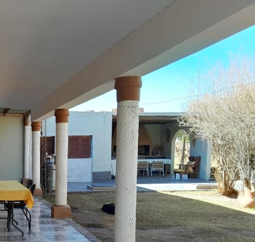 un patio con columnas, mesa y sillas en Bodega y Alojamiento Don Vega 2, en Tinogasta