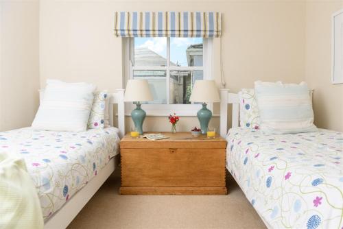 a bedroom with two beds and a table with two lamps at Mousehole Cottage in Penzance